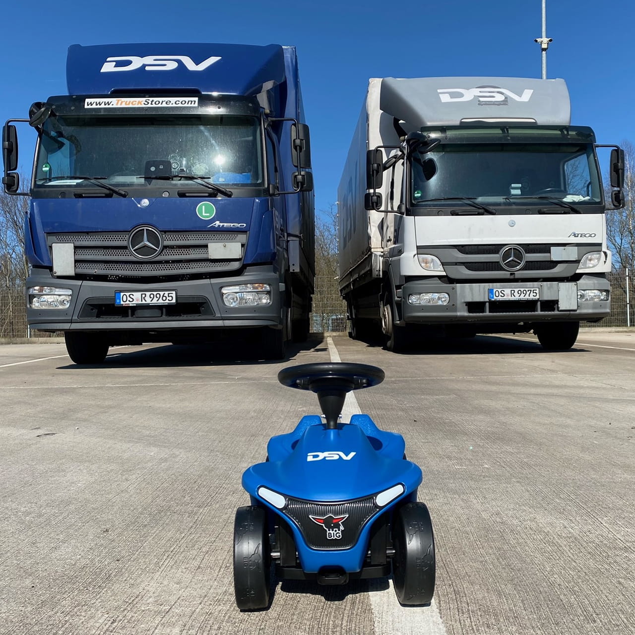 DSV Bobbycar vor zwei DSV Lkws